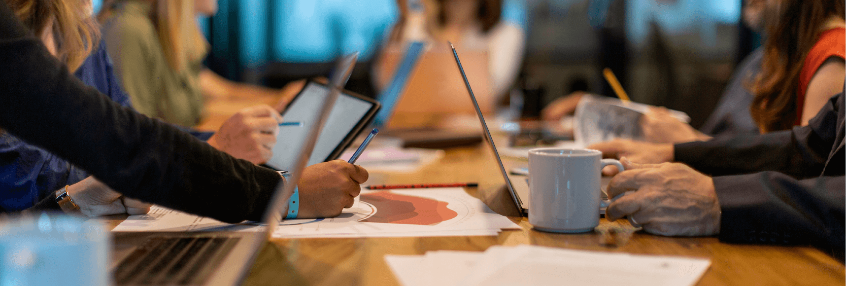 Company meeting of people on laptops and table